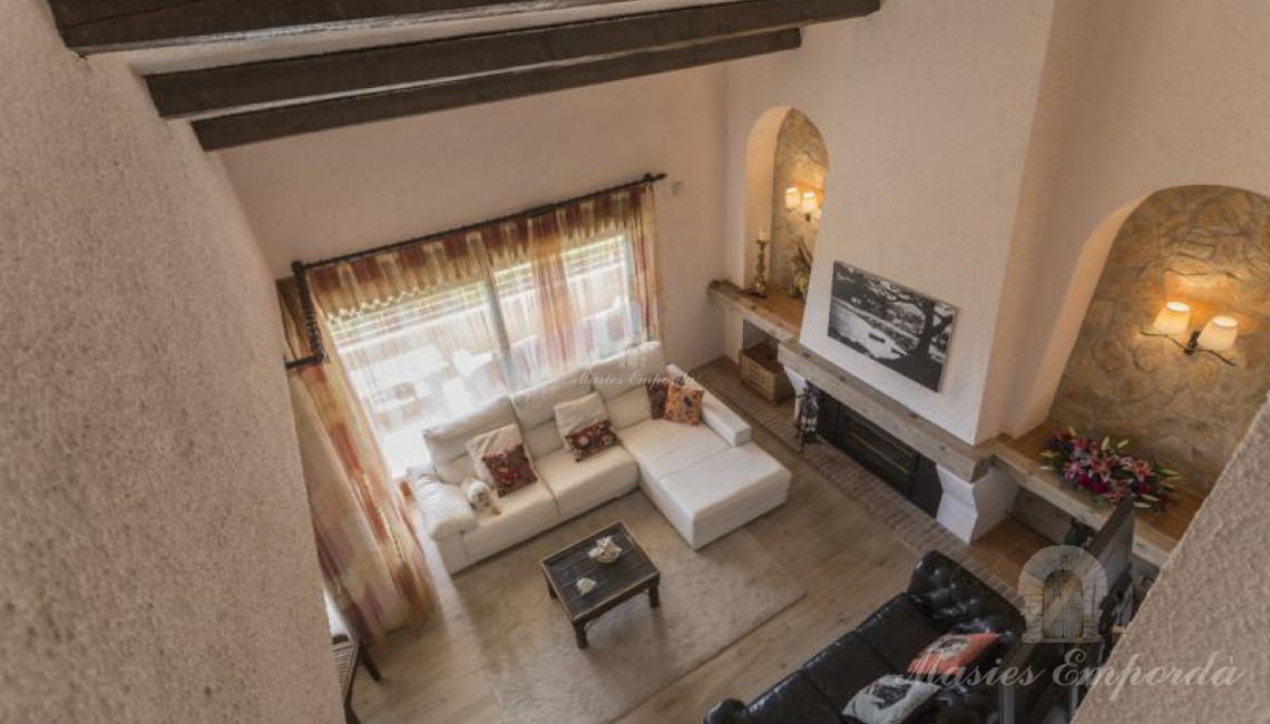 Vista cenital del salón principal de planta a doble altura de la casa con chimenea. 