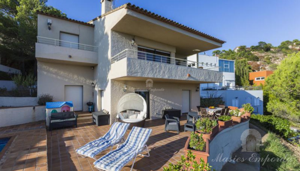 Detalle de la casa desde la piscina, donde se aprecia la terraza solárium y el jardín
