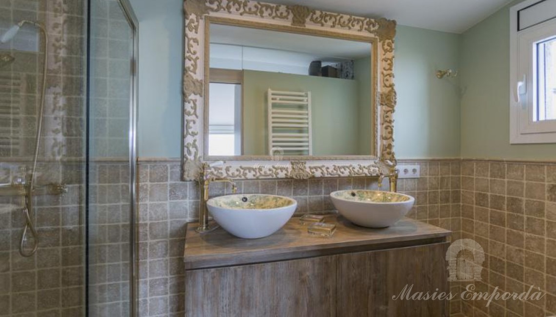 Baño completo con ducha de la suite, con detalle de piedra de travertinos en las paredes.