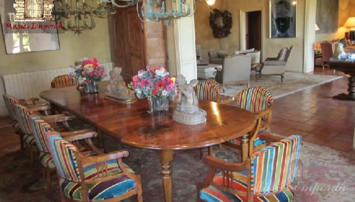 Comedor de la casa con mesa de madera de cerezo con sillas con tapizado de colores y vista del salón hall de entrada 