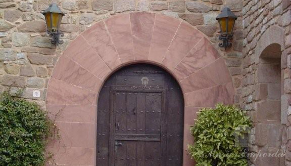 Detalle de la puerta principal a la Masía con el arco en piedra rosada tan característica de la zona de Bages.   
