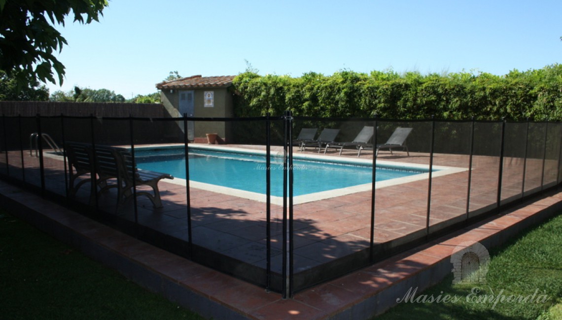 Vista de la piscina vallada como protección para niños y parte del jardín