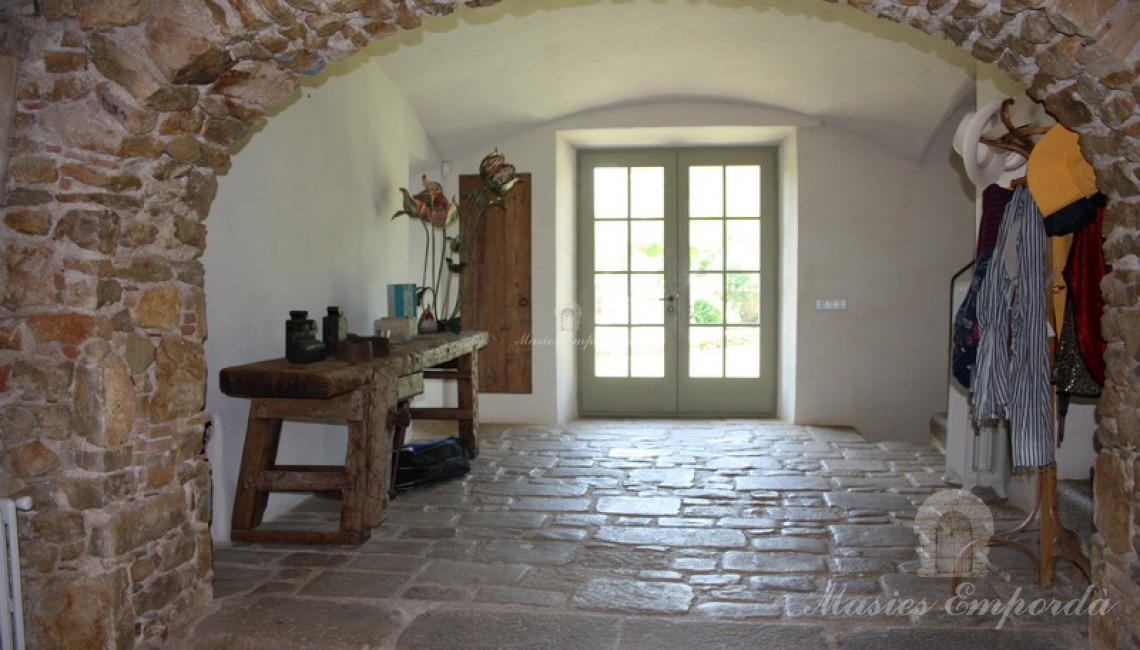 Hall abovedado de la casa con arco de medio punto de piedra en primer plano