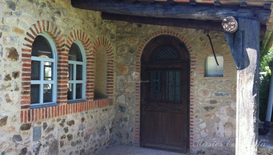 Detalle de puerta de forja y porche de vigas de madera y cubierta de teja