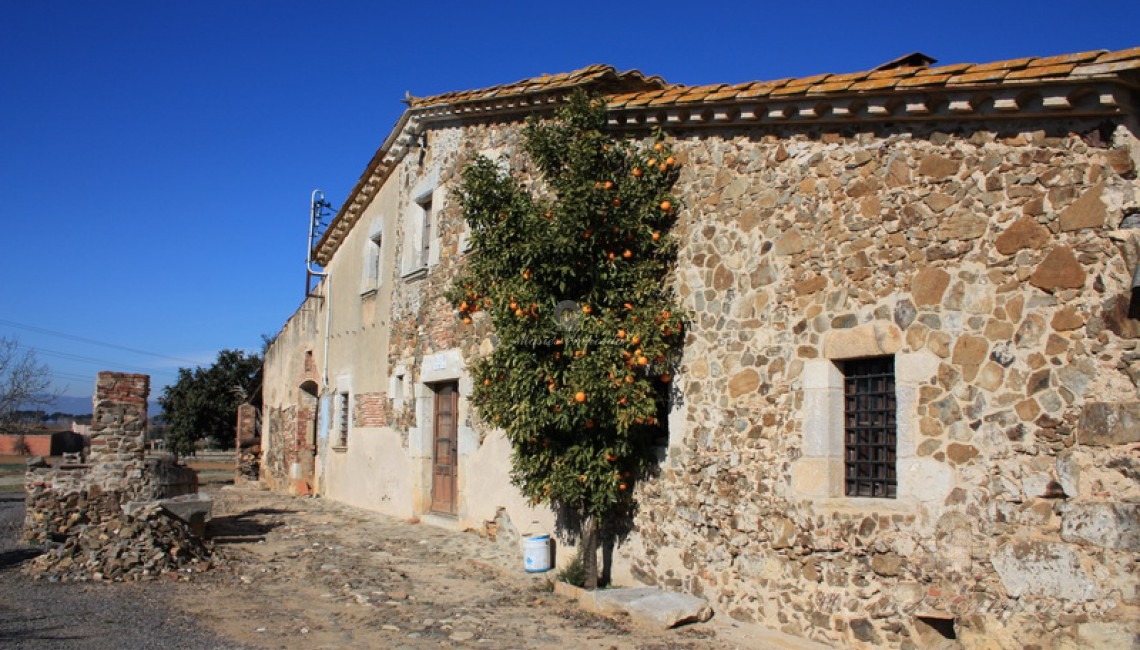Vista lateral de la fachada de la Masía y el pozo 