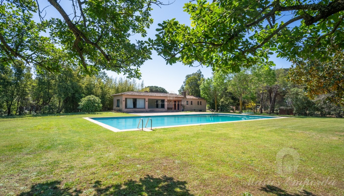 Vistas de la zona de piscina con al pabellón al fondo