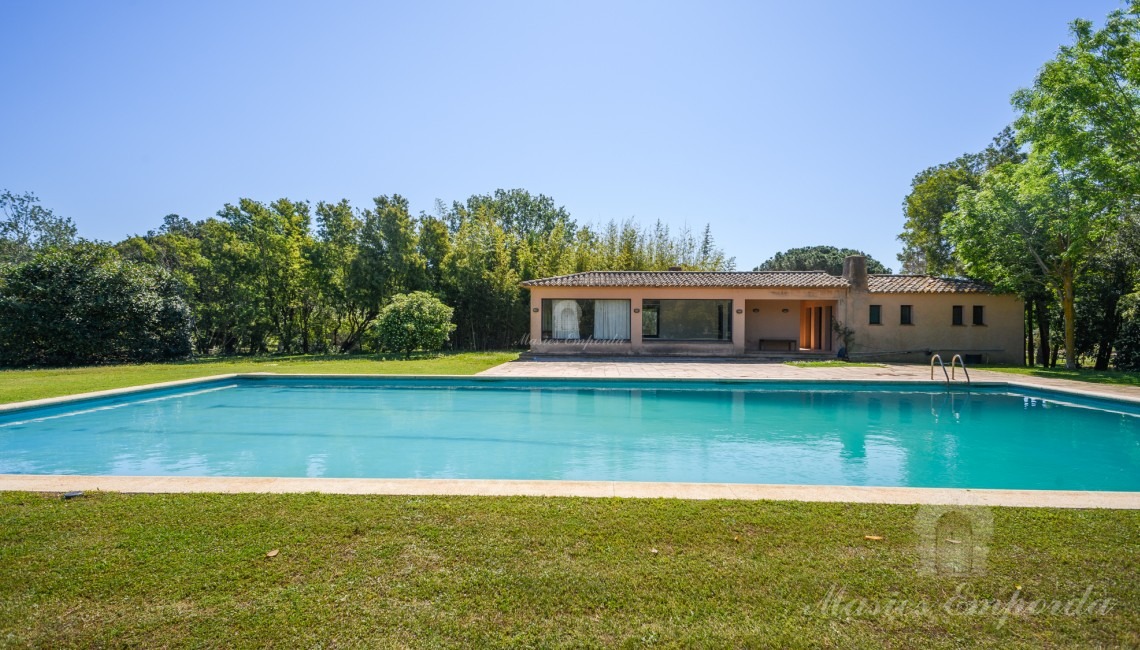 Vistas de la zona de piscina con al pabellón al fondo