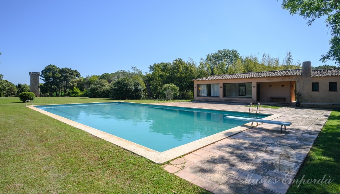 Vistas de la zona de piscina con al pabellón al fondo