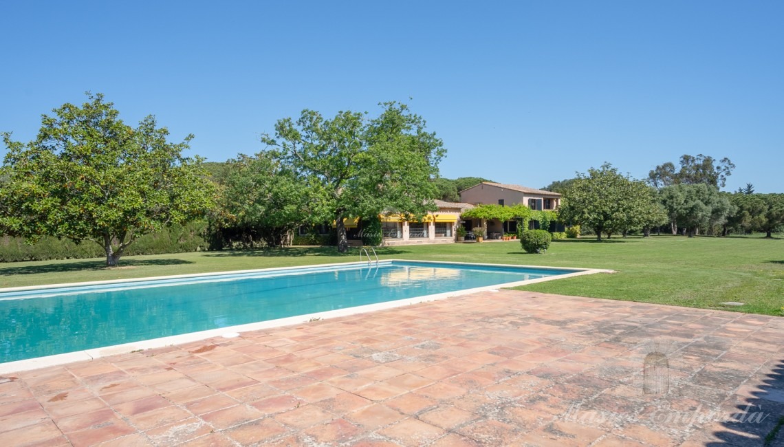Vistas de la zona de piscina con al pabellón al fondo