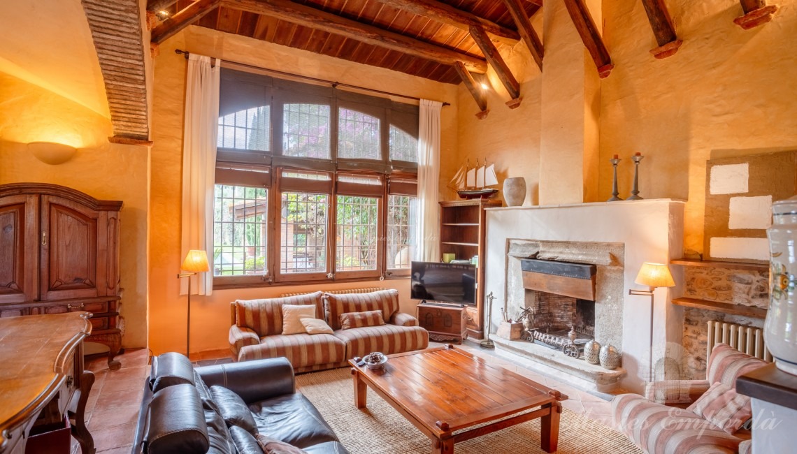 Salón a doble altura con chimenea y vistas al jardín