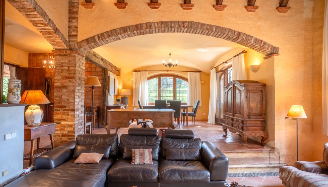 Salón a doble altura con chimenea con vistas al salón comedor y al jardín