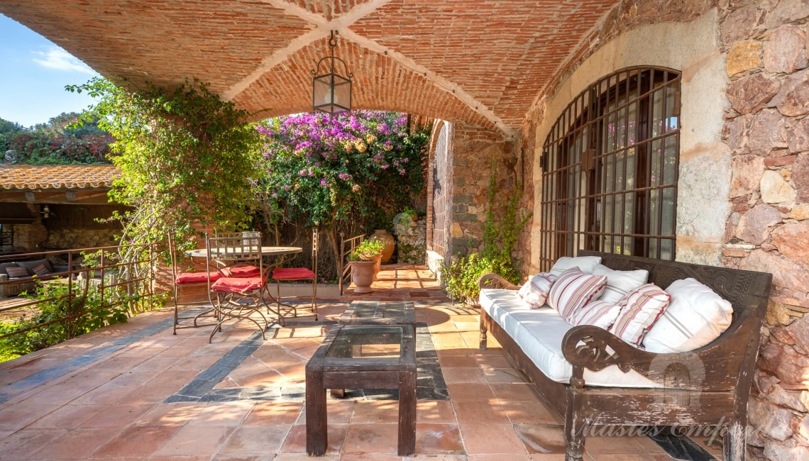 Porche de la casa con una cubierta de arco de crucería con acceso al jardín y piscina
