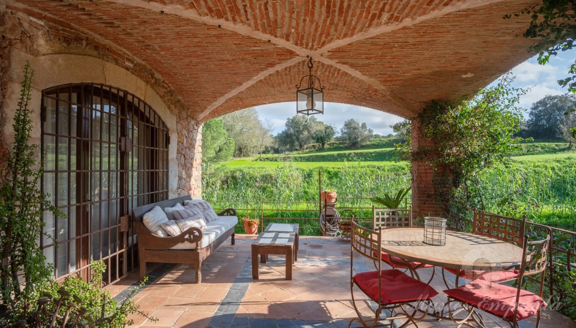 Porche de la casa con una cubierta de arco de crucería con acceso al jardín y piscina