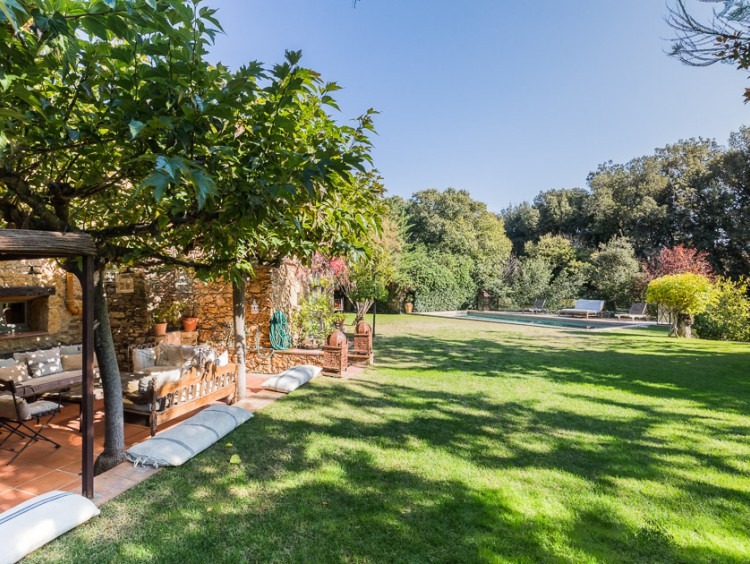 Vista del jardín y la piscina al fondo de la imagen 