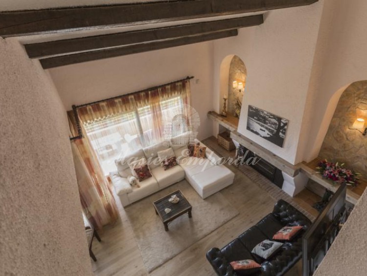Vista cenital del salón principal de planta a doble altura de la casa con chimenea. 