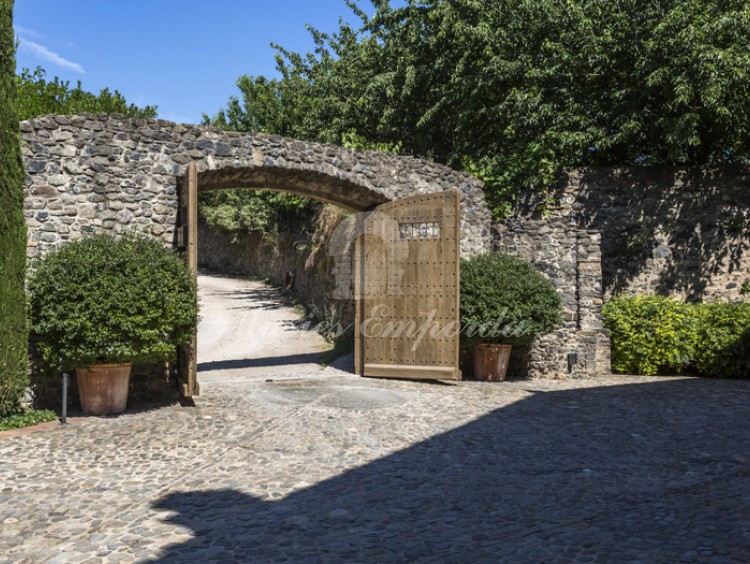 Muro de piedra y portón de madera que da acceso a la propiedad  