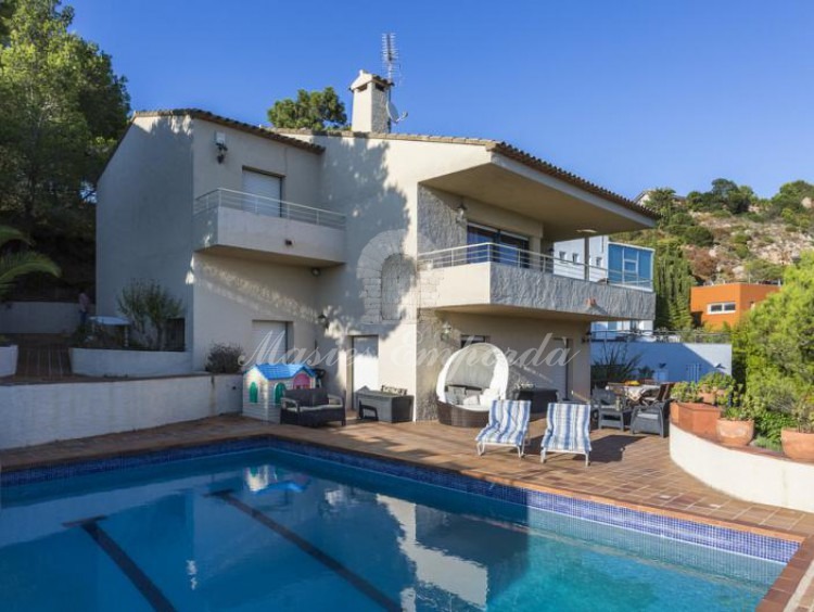 La casa desde la piscina, donde se aprecia la terraza solárium y el jardín