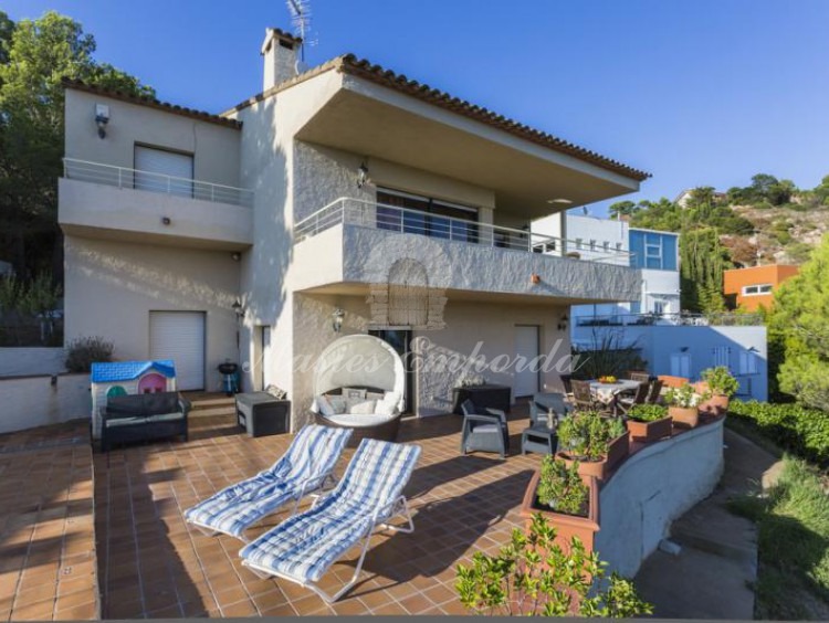 Detalle de la casa desde la piscina, donde se aprecia la terraza solárium y el jardín