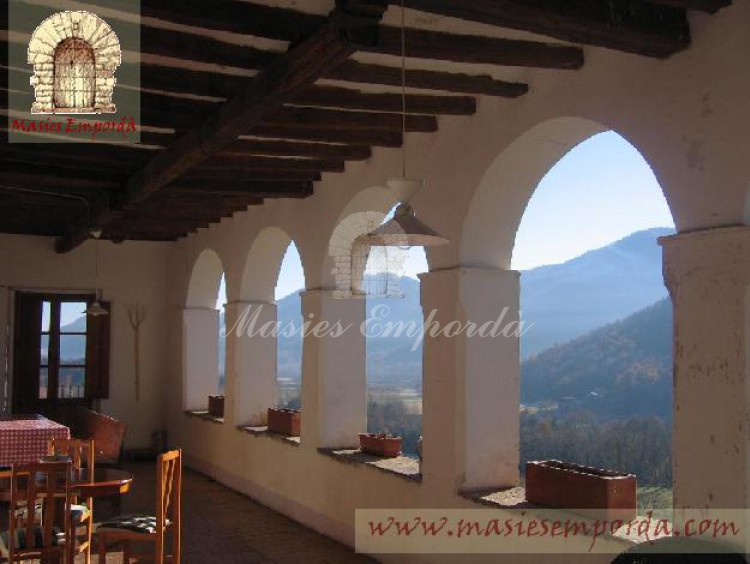 Terraza cubierta arcada con vista a los campos y bosque de la propiedad