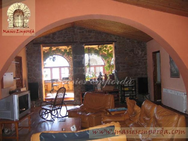 Vista del salón de estar de la masía principal con un gran arco de medio punto en el centro de este