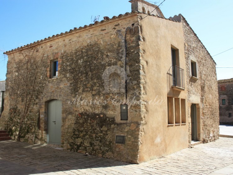 Vista de la fachada y el lateral de la casa de pueblo con entrada de vehículos en el lateral de esta 