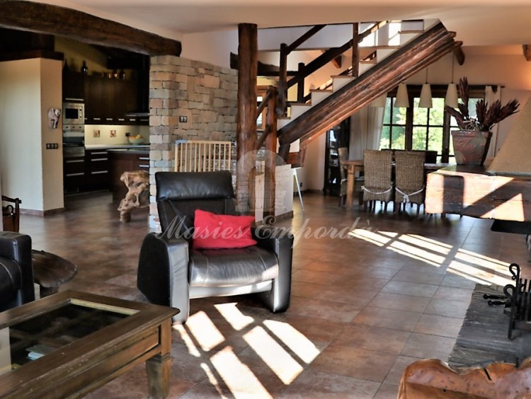 Vista del salón de estar de la casa con chimenea y el comedor al fondo de la imagen 